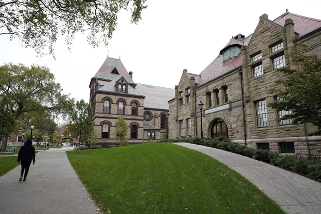 FILE - A pedestrian walks along a path on the campus of Brown University, in Providence, R.I., Monday, Oct. 12, 2020. (AP Photo/Steven Senne, File)