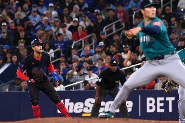 Toronto Blue Jays' George Springer (4) takes a lead off first base as Seattle Mariners starting pitcher Bryan Woo (22) throws to a Blue Jays batter in second inning MLB baseball action in Toronto on Friday, April 18, 2025. THE CANADIAN PRESS/Jon Blacker
