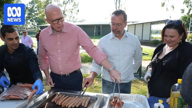 Two middle-aged men use tongs at a barbecue in the park.