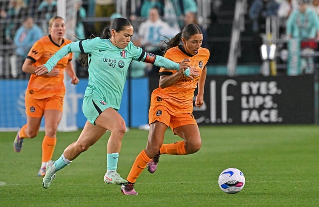Apr 19, 2025; Kansas City, Missouri, USA;  Houston Dash midfielder Barbara Olivieri (right) dribbles the ball up field against Kansas City Current midfielder Lo’eau LaBonta (left) in the second half at CPKC Stadium. Mandatory Credit: Peter Aiken-Imagn Images
