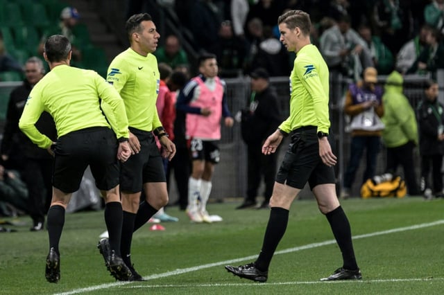 Referee Francois Letexier (right) checks on  assistant Mehdi Rahmoun (C) after halting play in Saint-Etienne