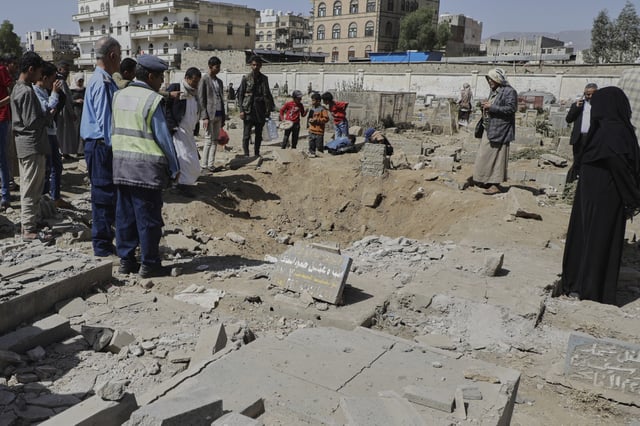Yemenis watch a crater of a explosion at Magel Al-Dammah cemetery a day after it was hit by U.S. airstrikes in Sanaa, Yemen, Sunday, April 20, 2025. (AP Photo)