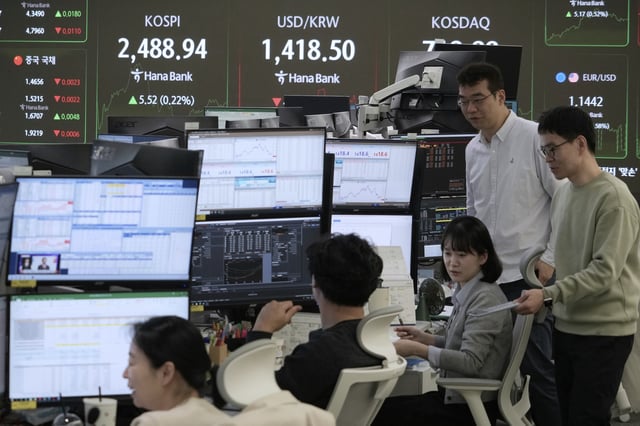 Currency traders work near a screen showing the Korea Composite Stock Price Index (KOSPI), top left, and the foreign exchange rate between U.S. dollar and South Korean won, top center, at the foreign exchange dealing room of the KEB Hana Bank headquarters in Seoul, South Korea, Monday, April 21, 2025. (AP Photo/Ahn Young-joon)