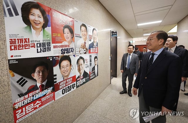 Kwon Young-se, the interim leader of the People Power Party, looks at the posters of the party's presidential hopefuls attached to a wall at the National Assembly in Seoul on April 21, 2025. (Yonhap)