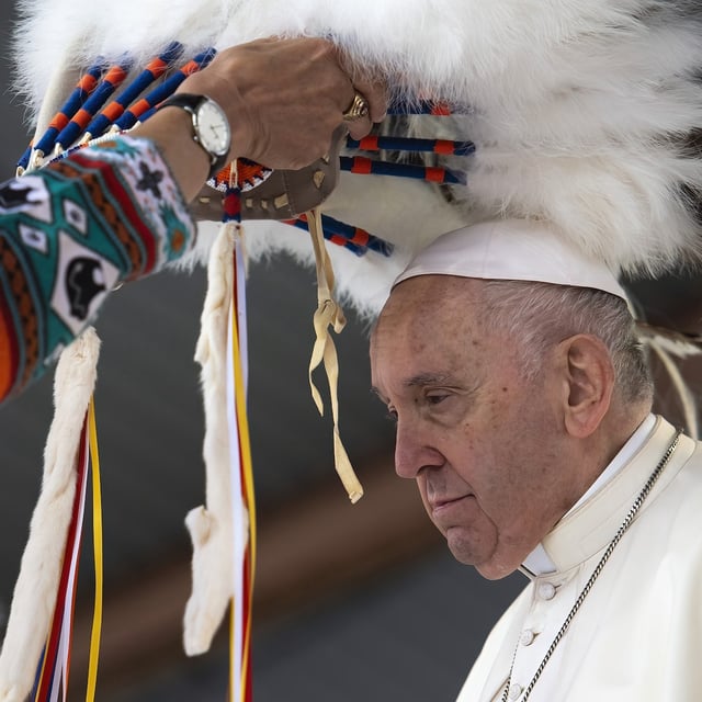 A headdress is placed on the head of Pope Francis following his apology for the residential school system at Maskwacis on July 25, 2022.