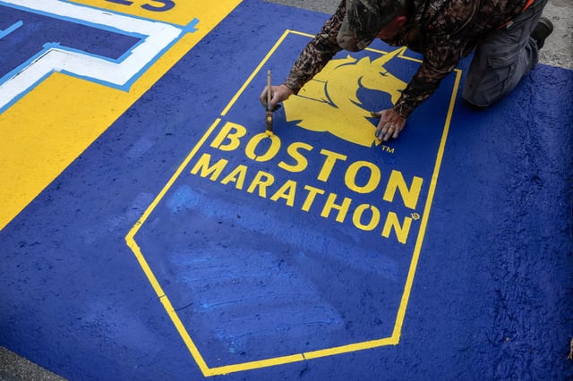 Hopkinton, MA – April 16: An employee of Mission Turf Services works on painting the starting line for the 129th Boston Marathon. (Photo by Craig F. Walker/The Boston Globe via Getty Images)