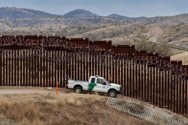 A Border Patrol officer sits inside his car at the fence in Nogales, Ariz., in 2019.