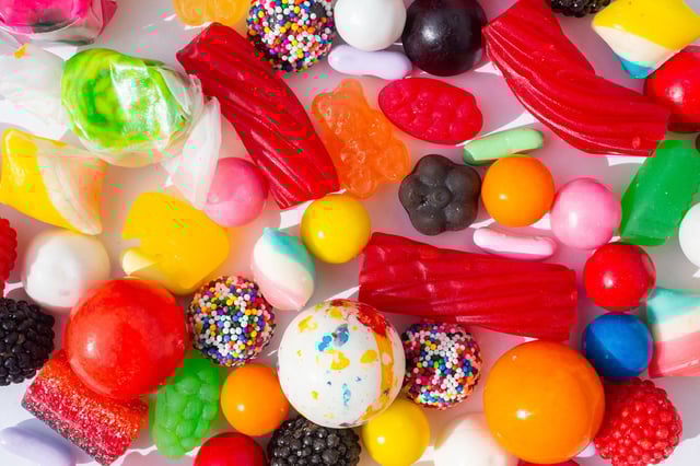 Colorful candy background, candy closeup. Sugar concept for sweets and treats, unhealthy eating junk food, or sugar rush indulgence in childhood nostalgia. Candies include red licorice, gummy candy, chocolate nonpareils, gumballs, salt water taffy, peppermint candy, and jawbreaker candy. This image could also represent artificial flavor and artificial color food. Multi-colored large group of objects, candy on white background. Part of a series.