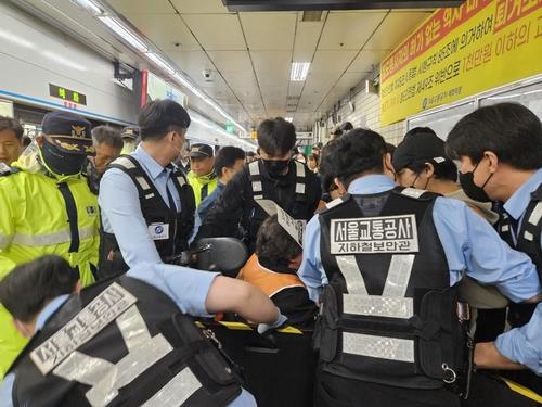 Seoul Metro subway security officers try to force a wheelchair-bound protester out of Hyehwa Station in central Seoul on April 22, 2025. (Yonhap)