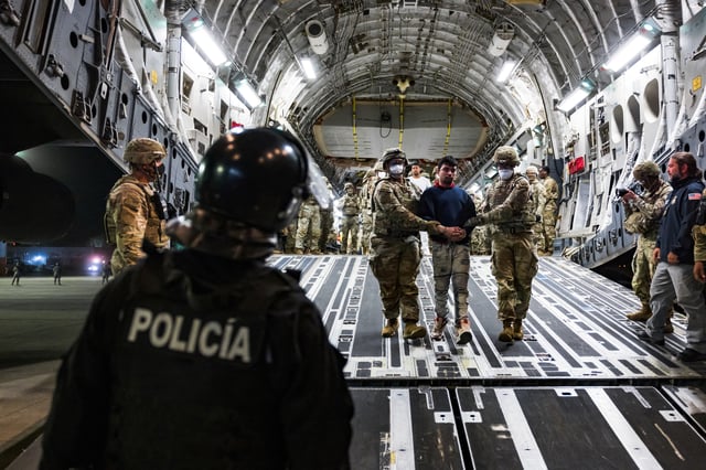 U.S. military personnel escort alleged members of the Venezuelan gang Tren de Aragua and the MS-13 gang recently deported by the U.S. government to be imprisoned in the Terrorism Confinement Center (CECOT) prison, at the El Salvador International Airport in San Luis Talpa, El Salvador April 12, 2025. Secretaria de Prensa de la Presidencia/Handout via REUTERS/File Photo