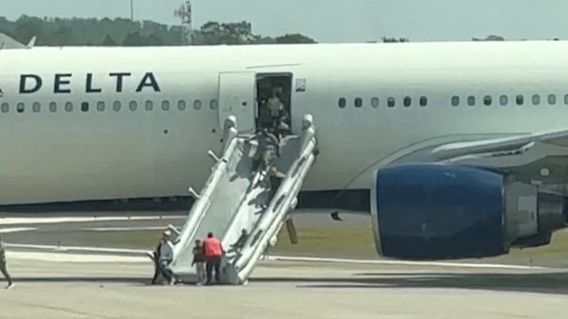 People evacuate a Delta plane due to an engine fire in Orlando, Florida, United States, April 21, 2025, in this video screengrab obtained from social media. 