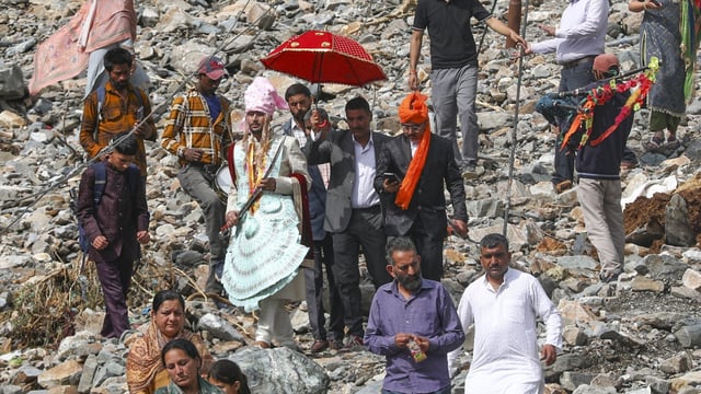 A groom along with his relatives walks towards his destination after roads were blocked by debris following heavy rain trigged landslides and flash flood, in Ramban district.