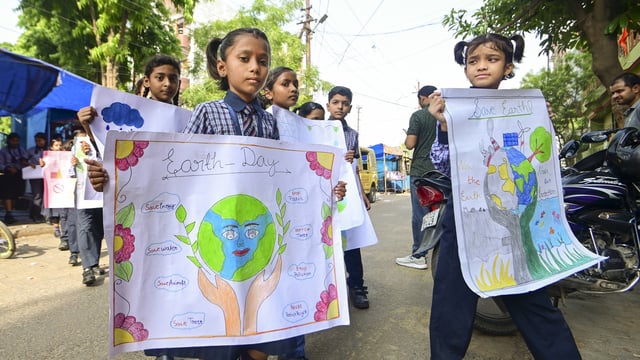 School children hold posters with message to save earth on the eve of 'Word Earth Day', in Prayagraj, Monday, April 21, 2025. 