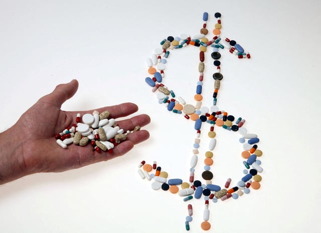Pharmaceutical tablets and capsules are arranged in the shape of a U.S. dollar sign on a table in this picture illustration taken in Ljubljana August 20, 2014.  REUTERS/Srdjan Zivulovic/File Photo