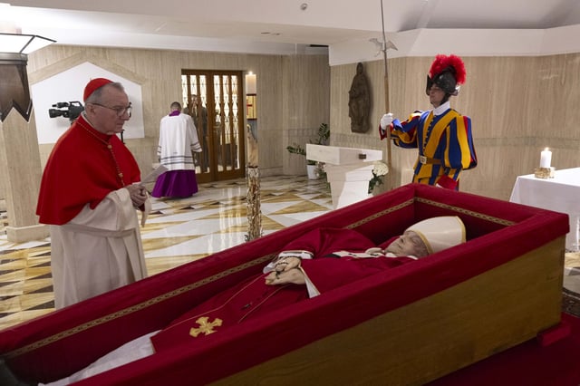 Vatican Secretary of State Cardinal Pietro Parolin, left, prays in front of the body of Pope Francis laid out in state inside his private chapel at the Vatican, Monday, April 21, 2025. 