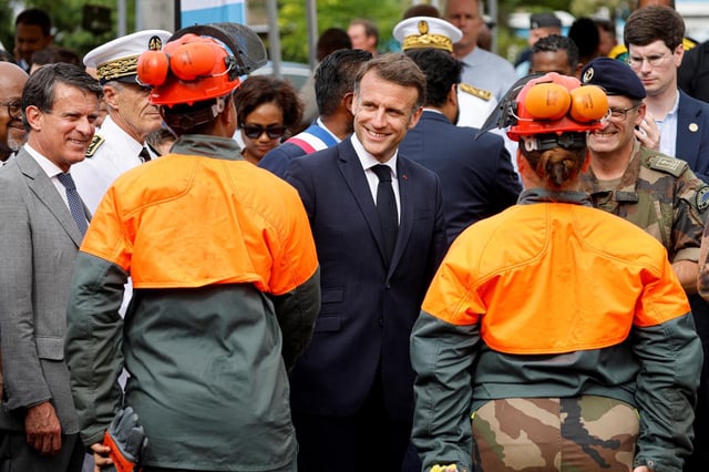 Emmanuel Macron (C), entouré du ministre des outre-mer Manuel Valls s’entretient avec des militaires qui luttent contre l’épidémie de chikungunya à Saint-Benoit (La Réunion), le 22 avril 2025. 
