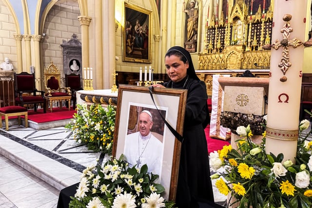 A nun attaches a black ribbon to a photo of Pope Francis following his death, at the Latin Patriarchate in Jerusalem's Old City, April 22, 2025. REUTERS/Sinan Abu Mayzer