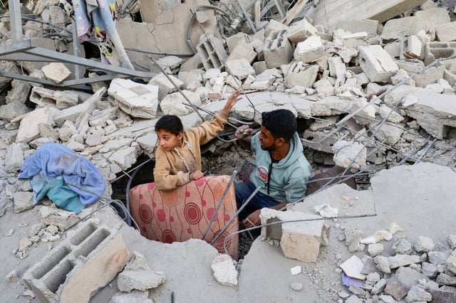 Zwei Jungen zerren eine Matraze aus den Trümmern eines zerbombten Hauses in Khan Younis Gaza