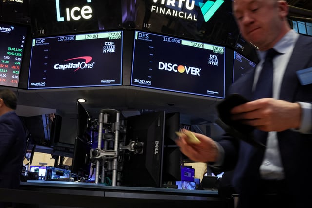 Screens display the logos and trading information for Capital One Financial and  Discover Financial as traders work on the floor at the New York Stock Exchange (NYSE) in New York City, U.S., February 20, 2024.  REUTERS/Brendan McDermid