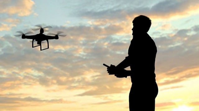 man operating of flying drone quadrocopter at sunset