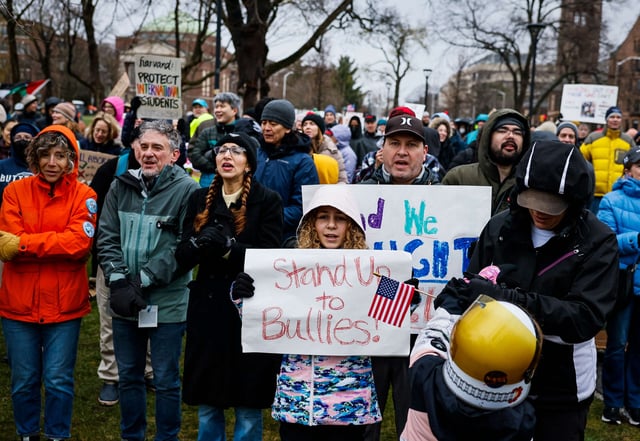 Protesters hold signs including 'Harvard: Protect International Students' and 'Stand Up to Bullies!' during a Cambridge Common rally on April 12, 2025, in Cambridge, Massachussetts.