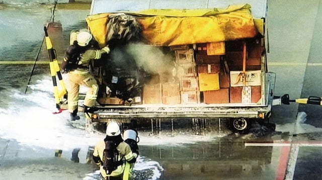 Feuerwehrleute löschen den Brandsatz in einem Paketwagen am Leipziger Flughafen.