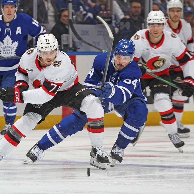 Ridly Greig of the Ottawa Senators battles for the puck against Auston Matthews of the Toronto Maple Leafs during the third period in Game 2 of the first round of the 2025 Stanley Cup Playoffs at Scotiabank Arena on April 22, 2025 in Toronto.