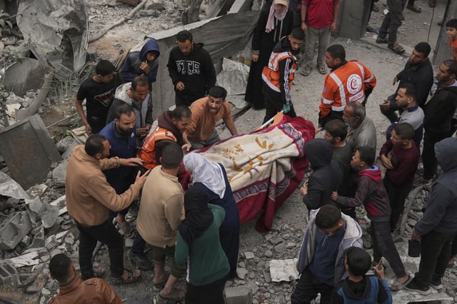 Voluntarios y trabajadores de emergencias retiran un cadáver de entre los escombros tras un ataque israelí.