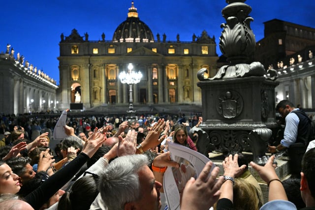 La foule rassemblée place Saint-Pierre cherche à recevoir l’édition spéciale du journal du Vatican, L’Osservatore Romano, annonçant la mort du pape François, le 21 avril 2025.
