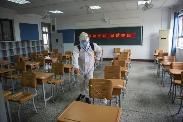 This photo taken on July 5, 2020, shows a staff member wearing protective clothing spraying disinfectant at an examination room ahead of the National College Entrance Examination in Wuhan in China&#39;s central Hubei province.