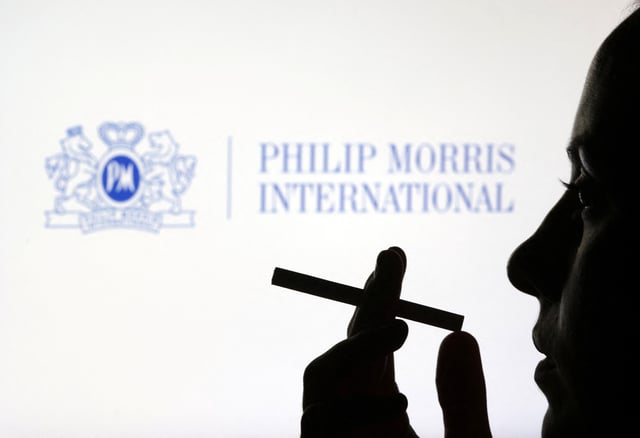 A woman poses with a cigarette in front of Philip Morris International logo in this illustration taken July 26, 2022. REUTERS/Dado Ruvic/Illustration