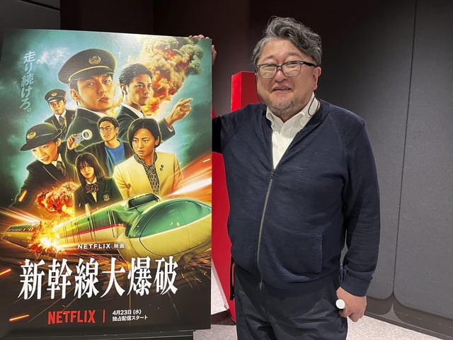 Shinji Higuchi, director of the Netflix film “Bullet Train Explosion,” poses next to the film’s poster at Netflix offices in Tokyo on Tuesday, April 22, 2025. (AP Photo/Yuri Kageyama)