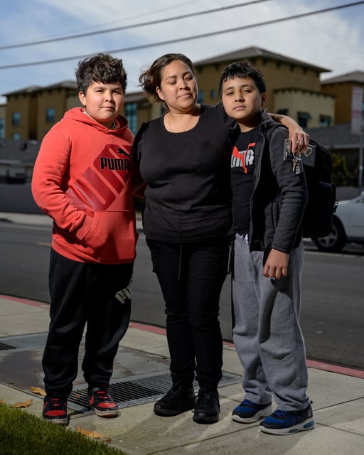 Elisa Morales, 39 stands next to her kids Alexis Valencia, 12, right, and Joaquin Valencia, 10, outside The Primary School, which is closing in 2026. Morales said the closure will be a "big change" for her and her kids.