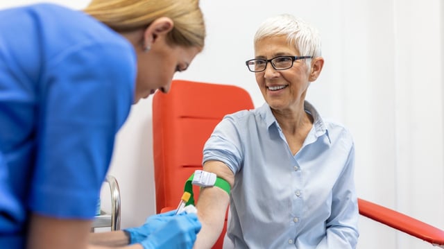 Medical technologist doing a blood draw services for patient. lab assistant with sterile rubber gloves taking blood sample from patient