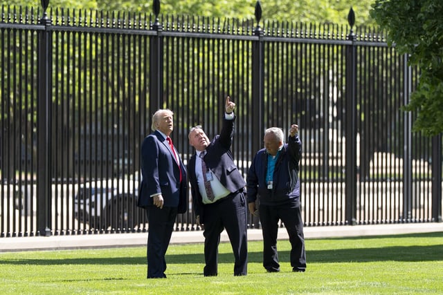 President Donald Trump, left, speaks with Dale Haney, head White House grounds keeper, right, and others, about a new flagpole on the North Lawn of the White House, Wednesday, April 23, 2025, in Washington. (AP Photo/Alex Brandon)