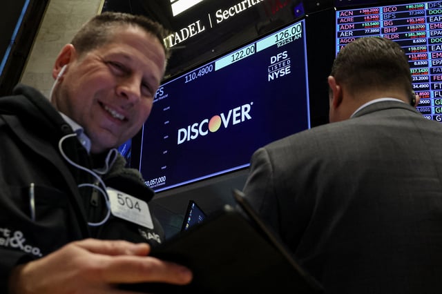 A screen displays the logo and trading information for  Discover Financial as traders work on the floor at the New York Stock Exchange (NYSE) in New York City, U.S., February 20, 2024.  REUTERS/Brendan McDermid