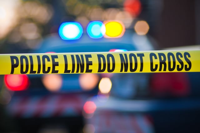 Stock image: Shallow depth of field image taken of yellow law enforcement line with police car and lights in the background.