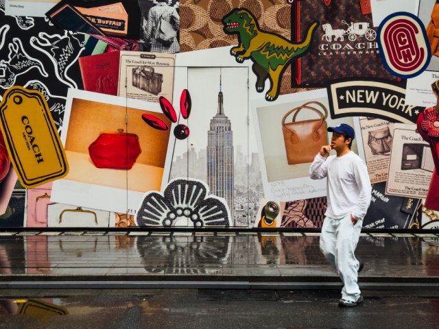 A man walks past a construction barrier outside a Coach store under renovation, decorated with iconic American elements including the Empire State Building, New York-themed graphics, leather goods, and Coach brand logos, on April 12, 2025 in Shenzhen, China. China has imposed a new round of retaliatory tariffs on U.S. imports, raising duties to 125% in response to the latest escalation by the United States, which increased tariffs on Chinese goods to 145%. The growing trade tensions have further impacted China's export sector, affecting key industries such as logistics, manufacturing, and cross-border e-commerce. The measures are part of Beijing's broader strategy to counter rising economic pressure and defend its trade interests. (Photo by Cheng Xin/Getty Images)