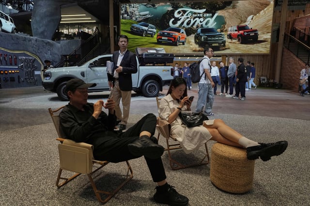 Visitors rest at the booth for US auto manufacturer Ford at the Shanghai auto show on Wednesday, April 23, 2025. (AP Photo/Ng Han Guan)