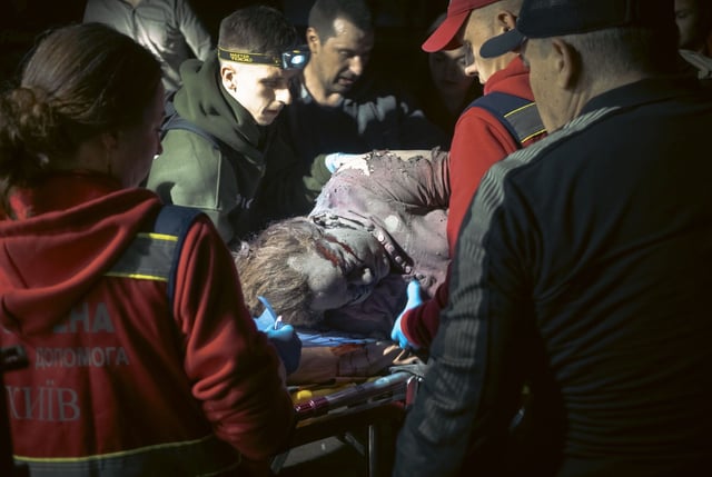 Rescatistas ucranianos transportan el cuerpo de una víctima en el lugar donde un cohete alcanzó un edificio residencial en Kiev.