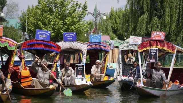 Shikara boatmen holding placards, distributed to them by a group of students, at Dal Lake in Srinagar on Thursday. They were protesting against the Pahalgam terror attack that left 26 tourists dead on Tuesday. (AFP Photo)