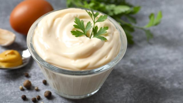 Bowl with mayonnaise and ingredients for cooking on gray background (Shutterstock)