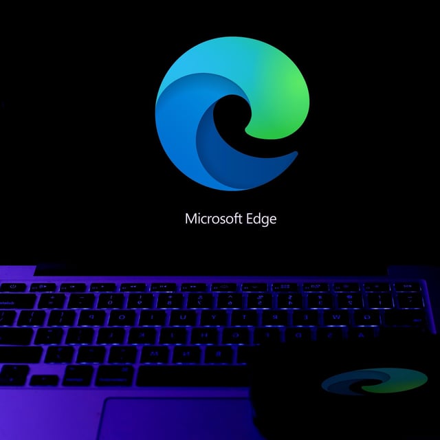 The Microsoft Edge logo on a black background displayed on a laptop screen.