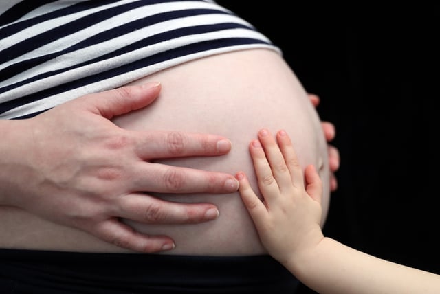 File photo of a child placing a hand on the stomach of a pregnant woman, taken December 31, 2017.