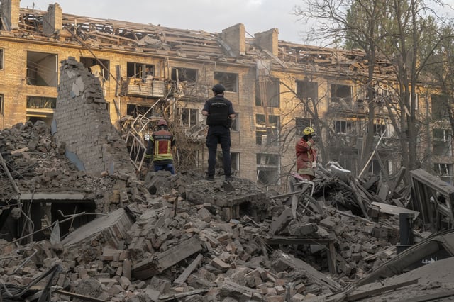 Des policiers et des membres du service d’urgence de l’État sur le site où trois missiles ont frappé un quartier résidentiel de Kiev.