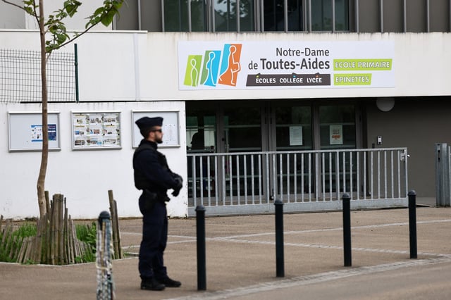 Un policier se tient devant l’institution Notre-Dame-de-Toutes-Aides où une lycéenne a été tuée dans une attaque au couteau commise par un élève du même groupe scolaire.