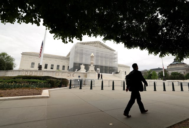 A person walks past the U.S. Supreme Court in Washington, D.C., U.S., April 21, 2025. REUTERS/Kevin Lamarque/File Photo
