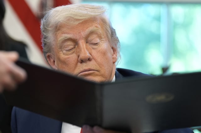 President Donald Trump being handed an executive order by White House staff secretary Will Scharf in the Oval Office of the White House, Wednesday, April 23, 2025, in Washington.