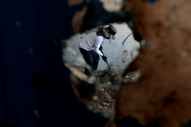 A member of the Guerreros Buscadores collective is reflected in a mirror searching for human remains in an abandoned house in western Mexico