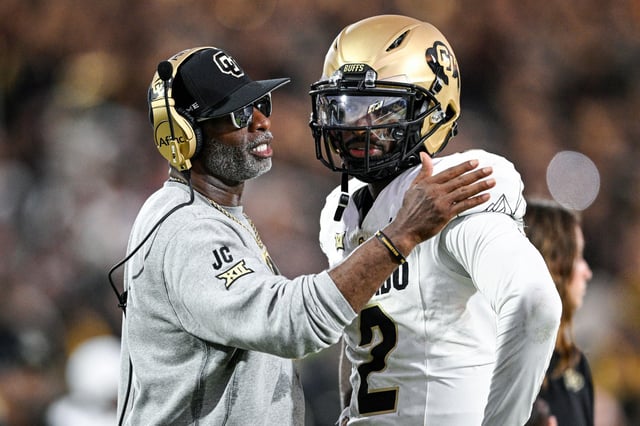 Colorado head coach Deion Sanders, left, talks with his son Shedeur Sanders during a game against Central Florida on Sept. 28, 2024.